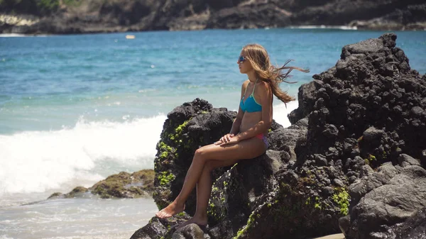 La chica se sienta en la roca y mira al mar. Bali, Indonesia — Foto de Stock