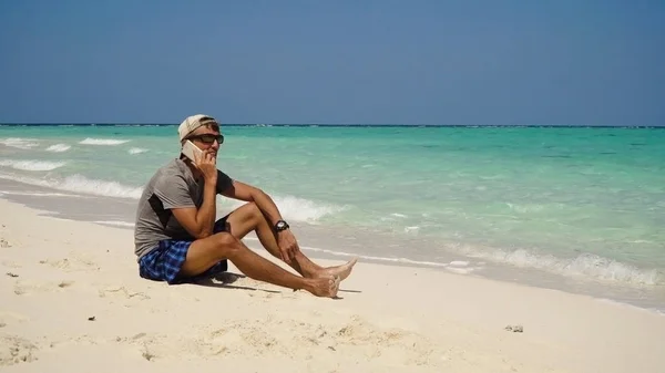 Un hombre con un celular en la playa . — Foto de Stock