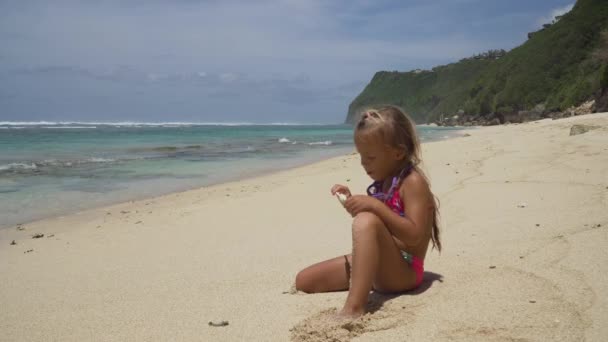 Holčička na pláži s lízátko. — Stock video