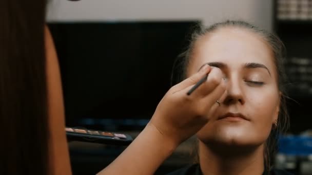 Maquillar artista haciendo profesional maquillaje de mujer joven — Vídeos de Stock