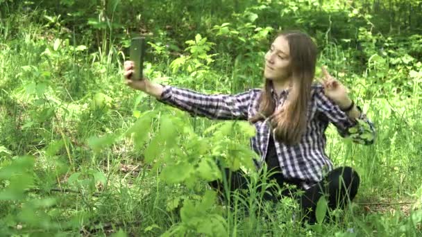 Chica utiliza una tableta en el bosque . — Vídeos de Stock