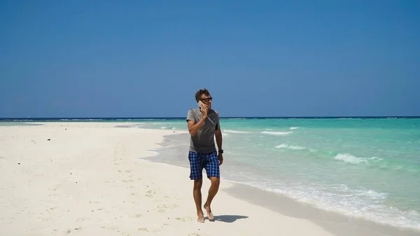 Un hombre con un celular en la playa . — Foto de Stock