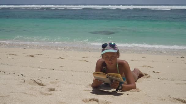 Menina na praia lendo um livro. — Vídeo de Stock