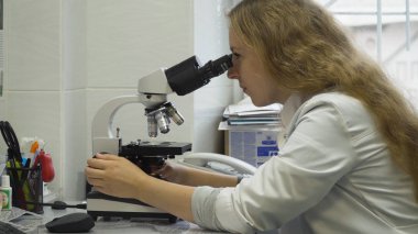 Kadın doktor mikroskoba bakar..
