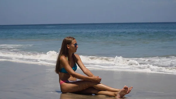 Ragazza sotto gli occhiali da sole si siede sulla spiaggia. — Foto Stock