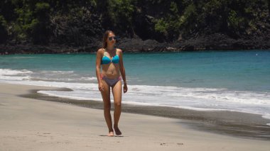 Kumsalda yürüyen bir kız. Bali, Endonezya.