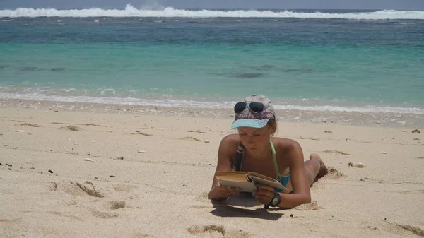 Chica en la playa leyendo un libro. — Foto de Stock