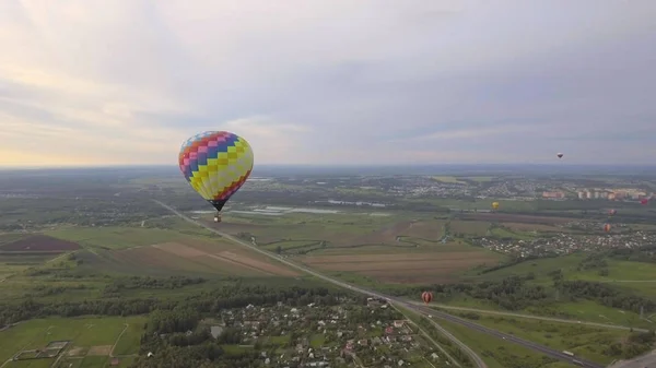 Globo de aire caliente en el cielo sobre un campo . — Foto de Stock