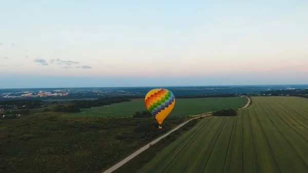 Globo de aire caliente en el cielo sobre un campo . — Foto de Stock