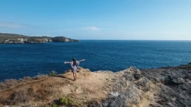 Mädchen, das auf einer Klippe steht und auf das Meer blickt. Bali, Indonesien — Stockvideo