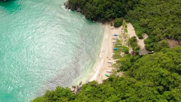 Rotsachtige eiland met een jungle en een turquoise lagune, uitzicht op de lucht. Caramoïsche eilanden, Filippijnen. Klein wit zandstrand. — Stockvideo