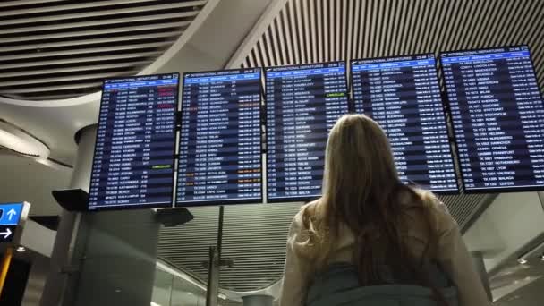 Woman in international airport looking at the flight information board. — Stock Video