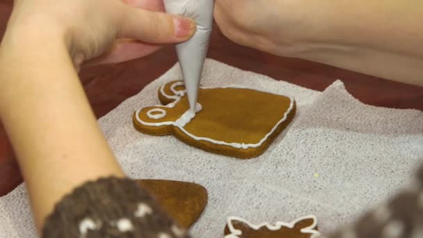 Woman decorates Christmas gingerbread with icing. — Stock Video