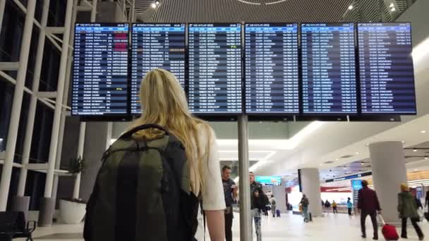 Mujer en el aeropuerto internacional mirando el tablero de información de vuelo. — Vídeos de Stock