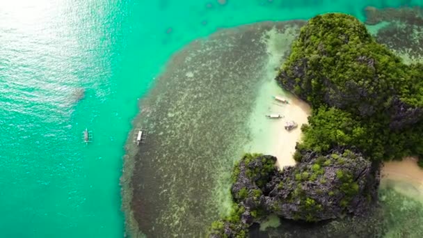 Rotsachtige eiland met een klein wit strand, antenne drone. Caramoïsche eilanden, Filippijnen. Zomer en reis vakantie concept. — Stockvideo