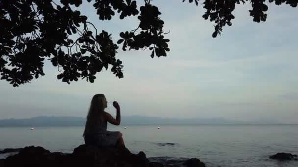 Una mujer disfruta de una puesta de sol en la playa. — Vídeos de Stock