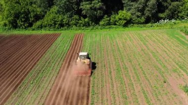 Patates tarlasında tarım makineleri toprağı işliyor.
