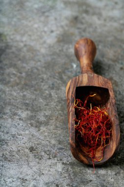 Kurumuş safran baharat iplikleri ahşap kepçeyle kırsal metal arka planda. Seçici odak.