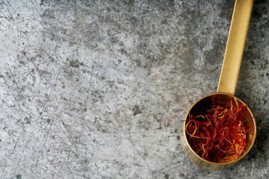 Kurumuş safran baharat iplikleri, bir ölçü kaşığının içinde, rustik metal arka planda. Üst Manzara. Boşluğu kopyala.