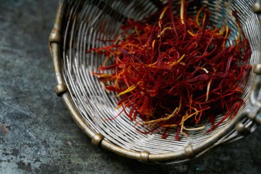 Kurutulmuş safran baharat iplikleri, eski model süzgeçte, rustik metal arka planda. Seçici odaklanma. Görüntüyü kapat.