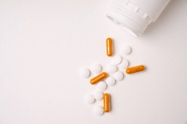Beyaz arka planda izole edilmiş beyaz plastik şişeden çıkan ilaç ve kapsüller. Üst Manzara. Boşluğu kopyala.