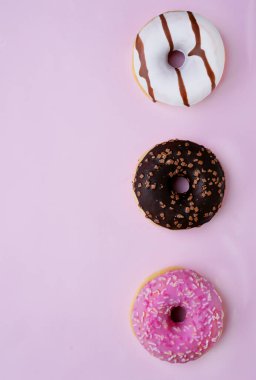 Jöleli, çikolata kaplı ve pembe arka planda izole edilmiş serpiştirilmiş donutlar. Üst Manzara. Boşluğu kopyala. 