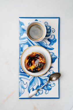 Pastel de nata. Geleneksel Portekiz tatlıları, yumurtalı tart ve mermer zemin üzerinde geleneksel Azulejo fayansları üzerinde bir fincan kahve. Üst görünüm