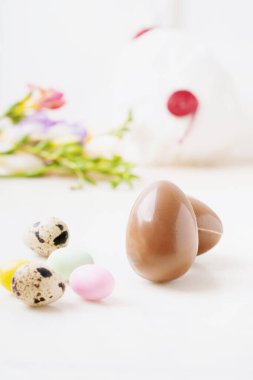 Pastel boyayla kaplanmış çikolatalı Paskalya yumurtaları ve beyaz arka planda bıldırcın yumurtaları. Mutlu Paskalyalar. Seçici odaklanma. Yan görünüm