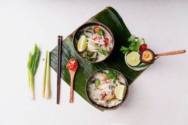 Geleneksel Tayland Tavuk Çorbası Tom Kha Gai hindistan cevizi kaselerinde taze limon, acı biber, kişniş, soğan ve şiitake mantarlarıyla servis edilir. Üst Manzara. Boşluğu Kopyala