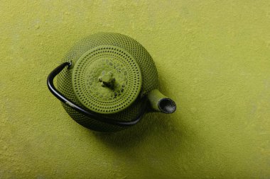 Matcha tea backgrounds: grren metal tea pot over the matching green matcha tea backgound clipart