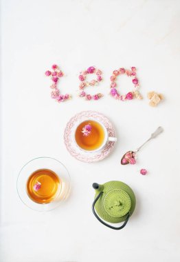 İki fincan bitki çayı ve beyaz mermer zemin üzerinde geleneksel oryantal çaydanlık. Yemek tipografisi. Kuru yerküre çiçeğinden yapılmış 