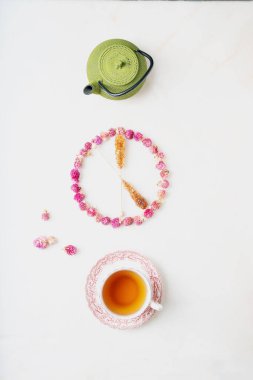 Bir fincan bitki çayı ve beyaz mermer arka planda geleneksel oryantal çaydanlık. Kuru yerküre çiçekleri ve çubukta şekerle süslenmiş. Saat 5 konsepti. Üst görünüm.