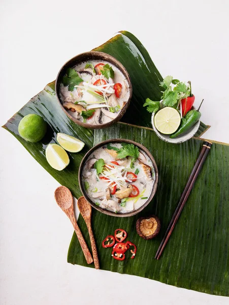 Geleneksel Tayland Tavuk Çorbası Tom Kha Gai hindistan cevizi kaselerinde taze limon, acı biber, kişniş, soğan ve şiitake mantarlarıyla servis edilir. Üst Manzara. Boşluğu Kopyala