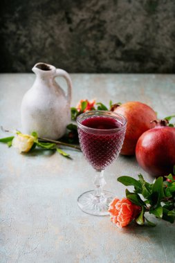 Kadehte ve sürahide nar meyveleriyle süslenmiş nar suyu kırsal arka planda çiçek açan dallar. Seçici odak noktası