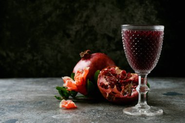 Nar meyveleri, tam ve yarım, bir bardak nar suyu, kırsal arka planda nar çiçeği dallarıyla süslenmiş. Yan görüş. Kapatın. Seçici odak