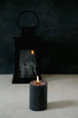 Ön planda yanan siyah mum arka plandaki klasik fener camına yansıyor. Seçici odaklanma. Kapat..