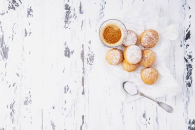 Pişirme kağıdına pudra şekeri serpiştirilmiş taze kızarmış mini çörekler ve rustik ahşap arka plan üzerine espresso. Üst Manzara. Boşluğu kopyala.