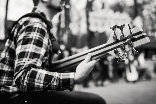 音乐人在人们面前的街道上玩六把弦乐无问题低音吉他的黑白照片. — 图库照片