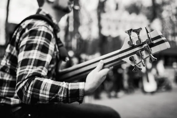 Zwart-wit foto van muzikant playng op zes tekenreeks fretloze basgitaar op de straat voor mensen. — Stockfoto