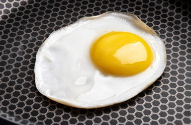 Tava yüzeyindeki sahanda yumurtanın yakın plan fotoğrafı.