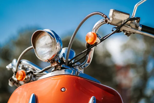 Closeup detalhe cromado e farol de scooter vintage retro laranja sob o céu azul e sol sobre o fundo borrado . — Fotografia de Stock