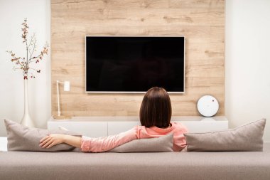 Kanepede tek başına ve karantinada oturan genç bir kadın. Evde kal. Kendine dikkat et. COVID-19 virüs koruma kavramı.