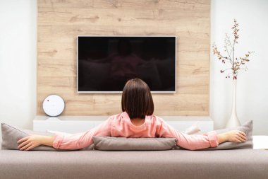 Kanepede tek başına ve karantinada oturan genç bir kadın. Evde kal. Kendine dikkat et. COVID-19 virüs koruma kavramı.