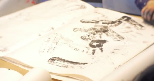 Κορίτσι δείχνει βρώμικα χέρια παιδιά γονείς σχεδιάζοντας μαζί βάζοντας γραμματόσημα επιστολές σε ένα χαρτί νηπιαγωγεία εμψυχωτές ψυχαγωγούν τις οικογένειες των παιδιών — Αρχείο Βίντεο