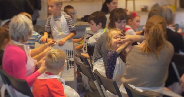 Окончание семейного мастер-класса в художественной галерее "Ополе" Дети и родители сидят, держа в руках свои картины — стоковое видео