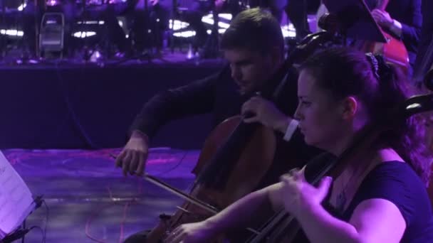 Concert symphonique rock Visite ukrainienne La chef d'orchestre de Kiev Nikolai Lysenko Une femme au premier plan Des musiciens jouent du violoncelle Des livres de musique sur les stands Illumination — Video