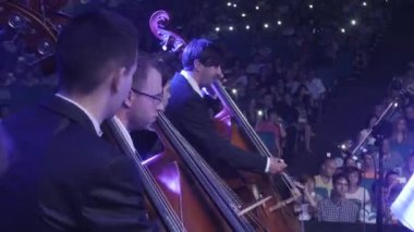 Rock Senfoni Ukrayna tur Kiev orkestra şefi Nikolai Lysenko erkekler müzisyenler konserde çello yayları müzik ile oynuyor kitaplar stand Mavi ışıklar