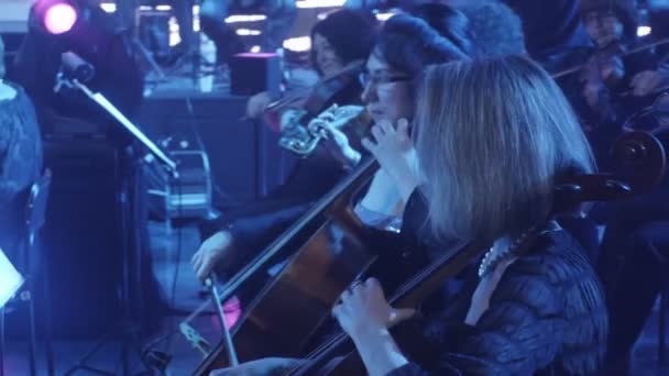 Rock Symphony Concert Oekraïense Tour Kiev dirigent Nikolai Lysenko vrouwelijke cellisten en violisten muzikanten spelen muziekboeken over Stands lichten — Stockvideo