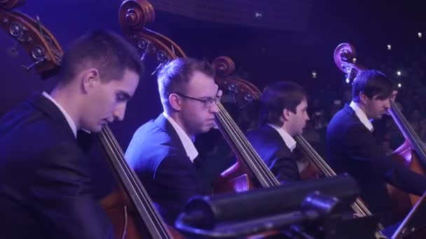 Rockkonsert Symphony ukrainska tur i Kiev dirigent Nikolai Lysenko män musiker spelar cello med en bågar musik böcker på stativ blå lampor — Stockvideo