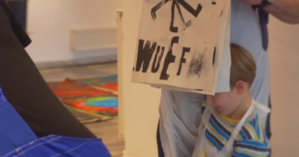 Famiglia Master Class Opole Art Gallery Kid mostra il suo disegno lettere stampate nere su disegno di carta per bambini Le persone applaudono animatori intrattenere i bambini — Video Stock